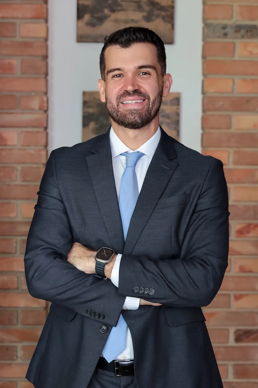 Dr. Tiago de Melo Pereira, advogado especialista em planos de saúde, em frente à parede de tijolos do escritório